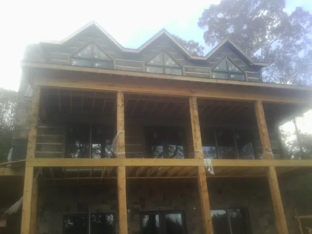 Dormers and porch framing on a large log home under construction — Roof Coating work by our crew in Higginsville