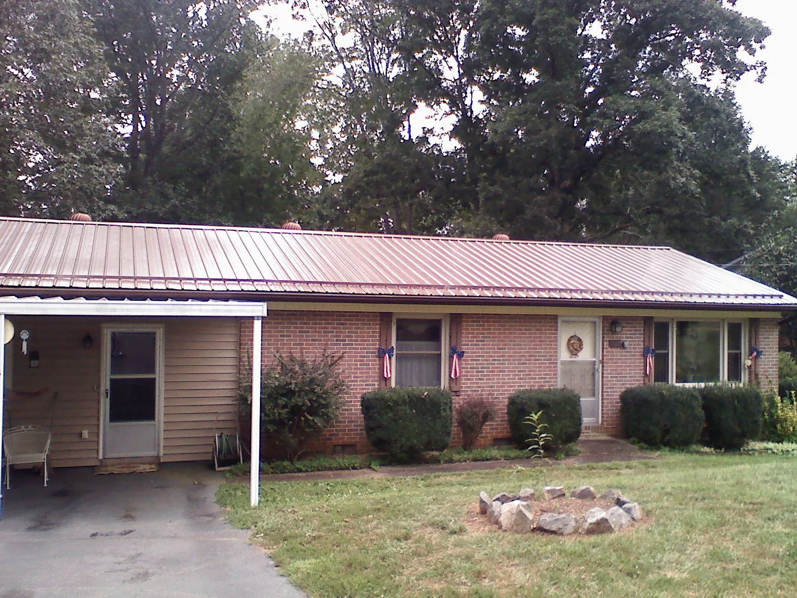 Bronze metal roof and carport on a brick ranch home — Roof Repair work by our crew in Higginsville