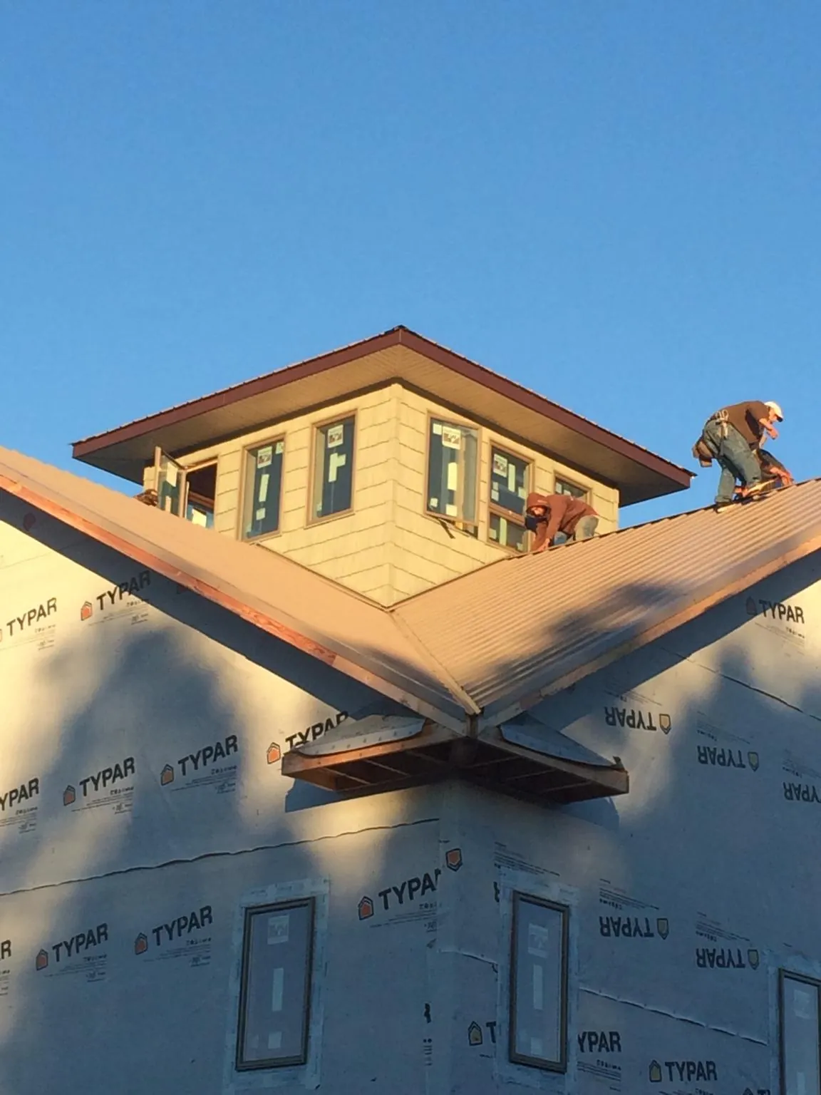 Roofers working around a rooftop cupola on a new metal roof at sunset — Roof Waterproofing in Higginsville by Roofing Brothers